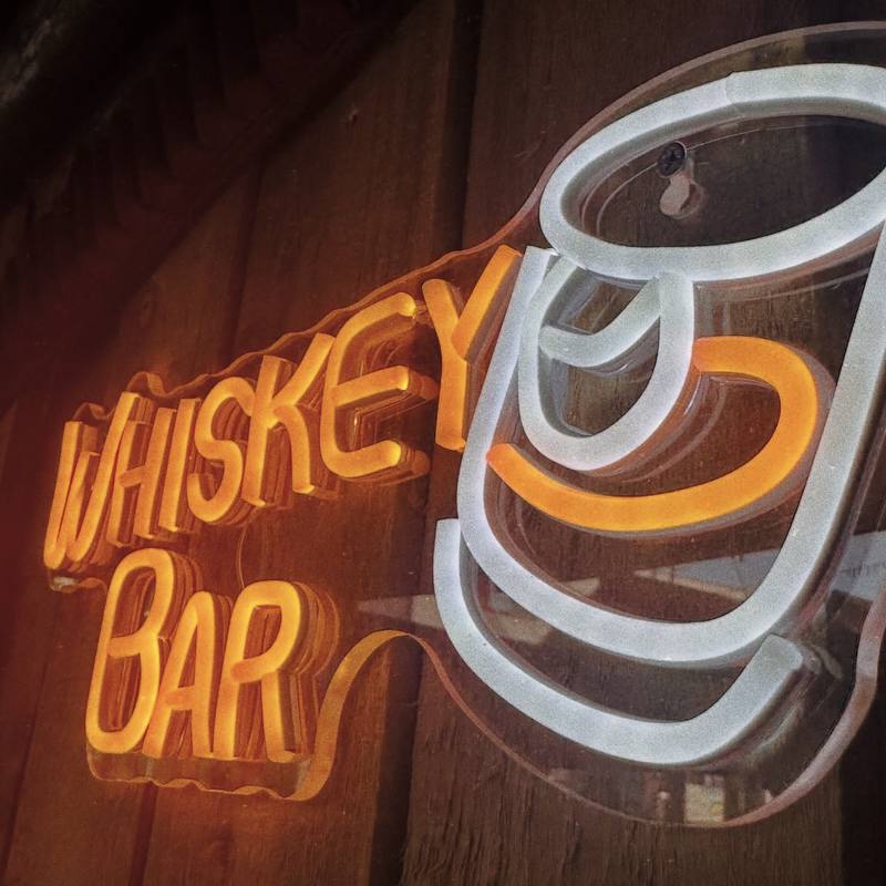 Orange and white neon sign reading Whiskey Bar